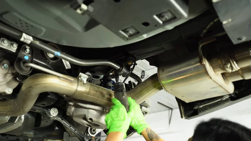 A mechanic bolting the sway bar into place with the new mounting bracket