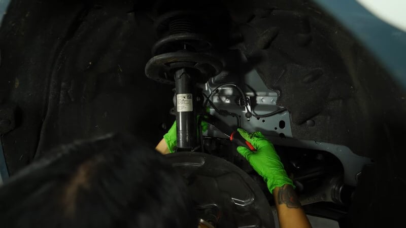 A mechanic using a clip removal tool to disconnect the brake line clips