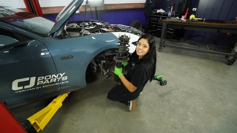 A mechanic holding the removed front strut for the camera to see