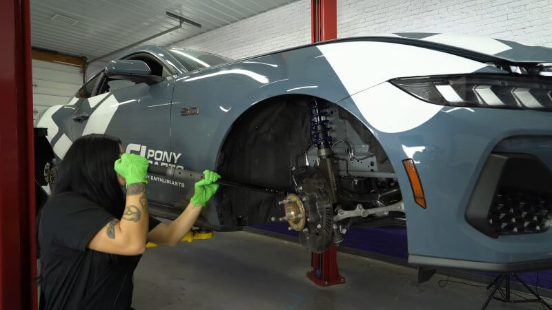 A mechanic using a torque wrench to tighten the factory strut nuts
