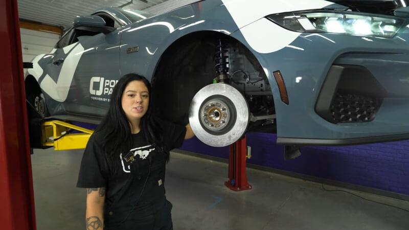 A mechanic standing in front of a reinstalled front brake rotor