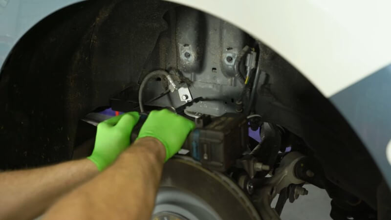 A mechanic drilling out holes to anchor the upper shock mount