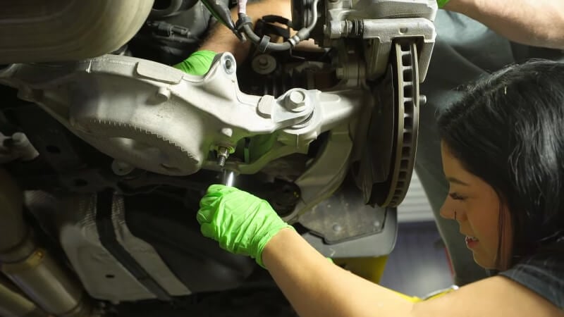 A mechanic tightening down a bolt to connect the lower shock mount to the lower control arm