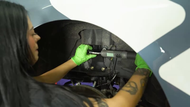 A mechanic tightening down the upper shock mount bolts with a torque wrench