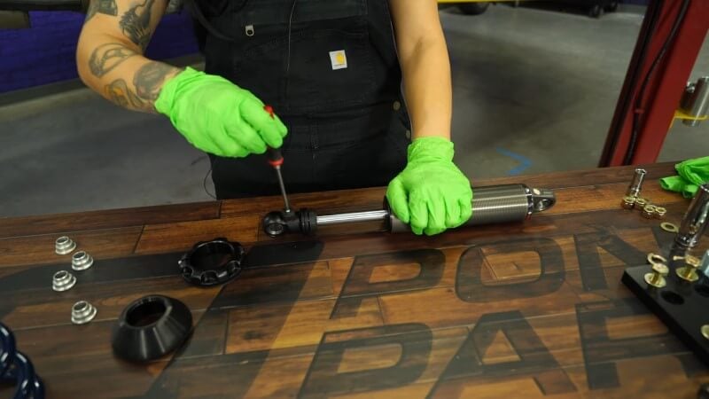 A mechanic unscrewing the adjustment knob on a Ridetech shock