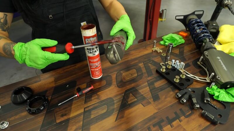 A mechanic spreading red assembly lube on a Ridetech shock