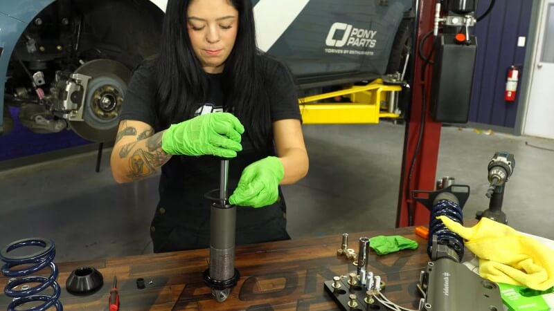 A mechanic sliding the delrin bushing into place on the top of the shock
