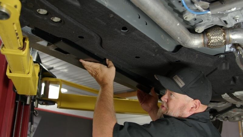 Mechanic aligning the jacking rail in place to ensure everything lines up