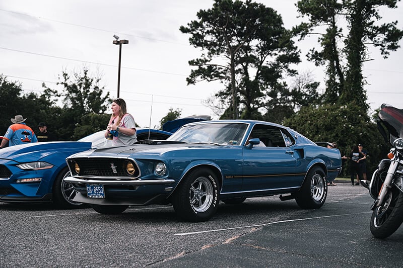 A Grabber Blue classic Mustang Mach 1 parked at a car show