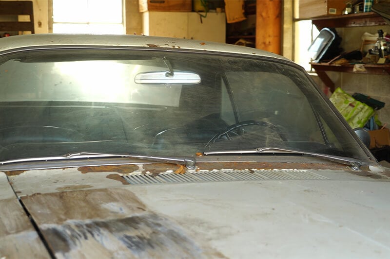 A close-up of a rusty classic Mustang in a garage