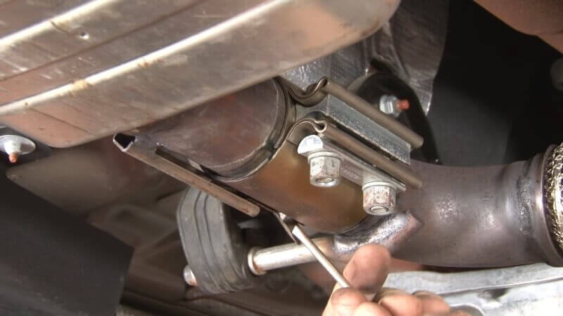 Mechanic removing the downpipe from the factory resonator on a Mustang EcoBoost