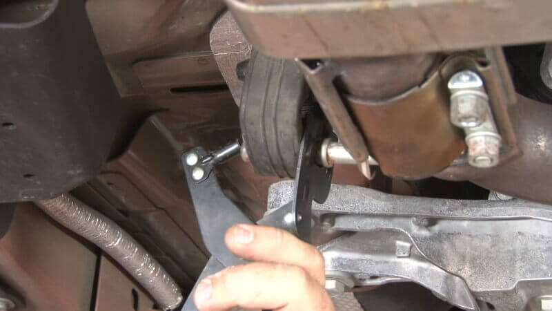 Mechanic unhooking the exhaust from the exhaust hanger on a Mustang EcoBoost