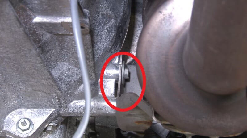 Mechanic removing the bracket on the side of the transmission on a Mustang EcoBoost