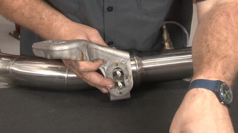 Mechanic installing stock components onto the new downpipe on a Mustang EcoBoost
