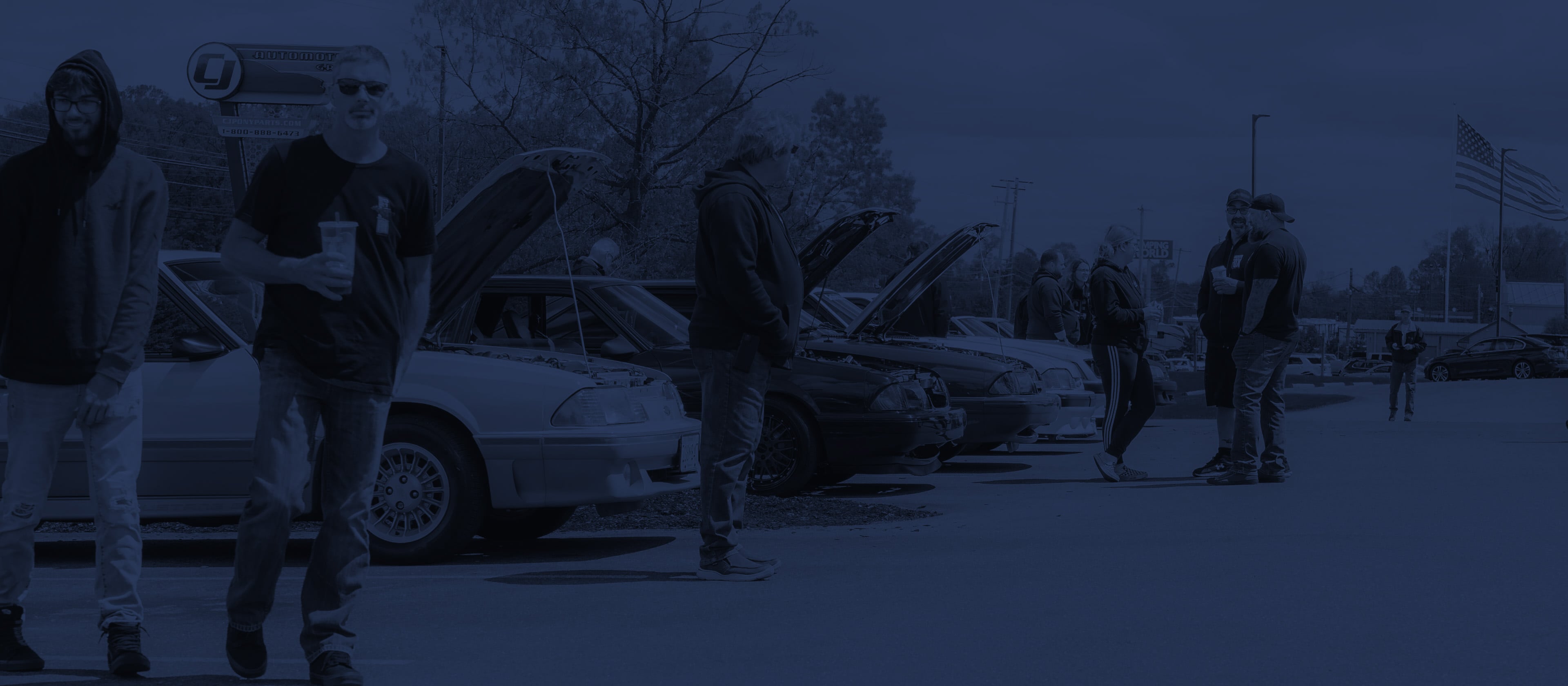 Mustang owners and enthusiasts gathering around an S550 Mustang at a car show